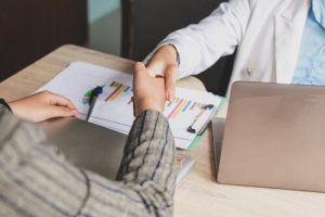 Employees shaking hands while discussing how to improve benefits communication