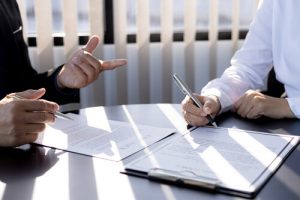 Two coworkers reviewing laws in a boardroom.